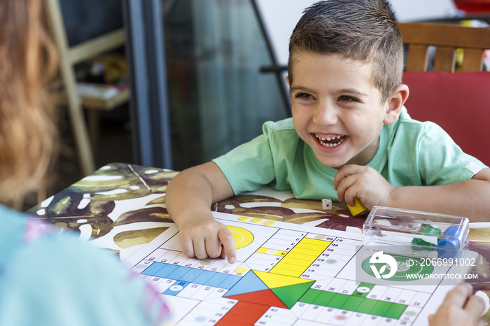 Little boy playing ludo with his mother on vacation