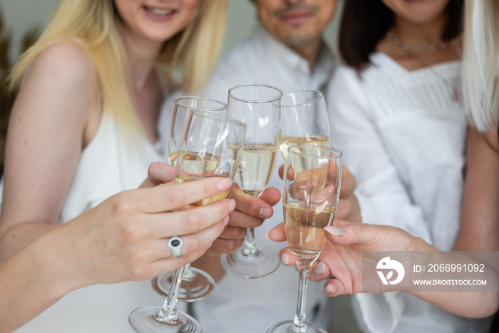 Close-up of friends hands holding glasses of champagne and making cheers. Corporate concept at work.