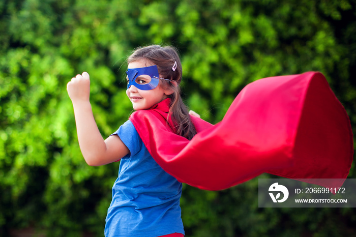 Superhero kid against green background outdoor. Childhood, success and and power concept