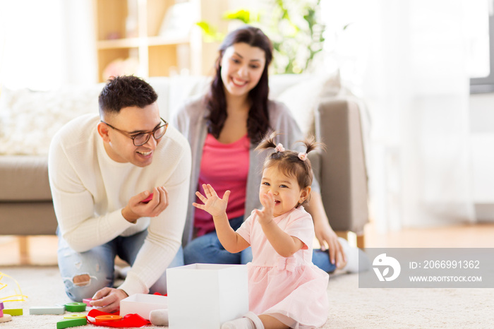 family, holidays and people concept - mother, father and happy little daughter with gift box at home birthday party