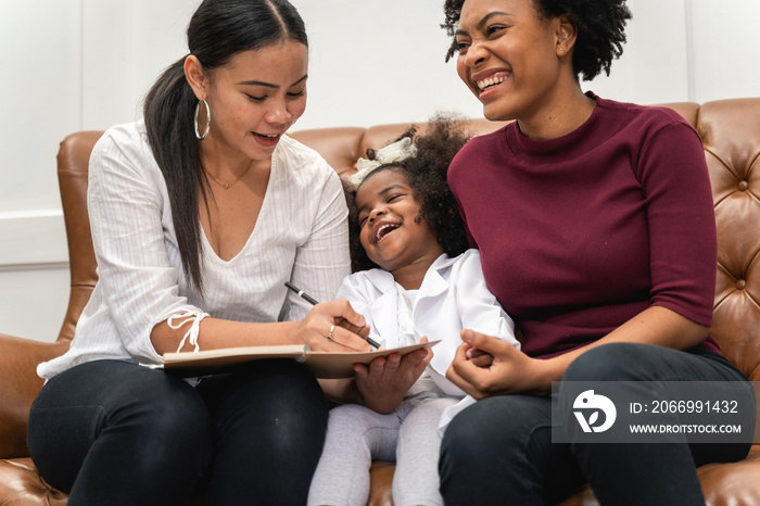 LGBT diversity Lesbian Couple Moments Happiness with her african girl laughing and drawing picture, LGBT lifestyle.