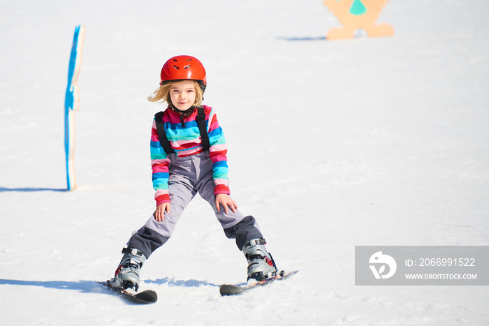 Child girl skiing in mountains. Active kid with safety helmet and goggles. Ski race for young children. Kids ski lesson in alpine school. Little skier racing in snow