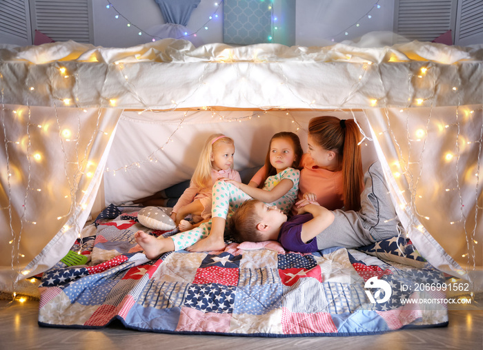 Young woman and cute children playing in hovel at home