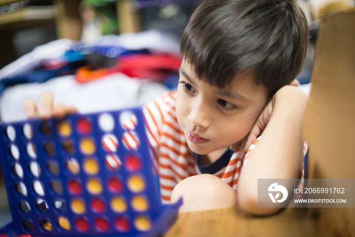 Little boy playing connect four game soft focus at eye contact