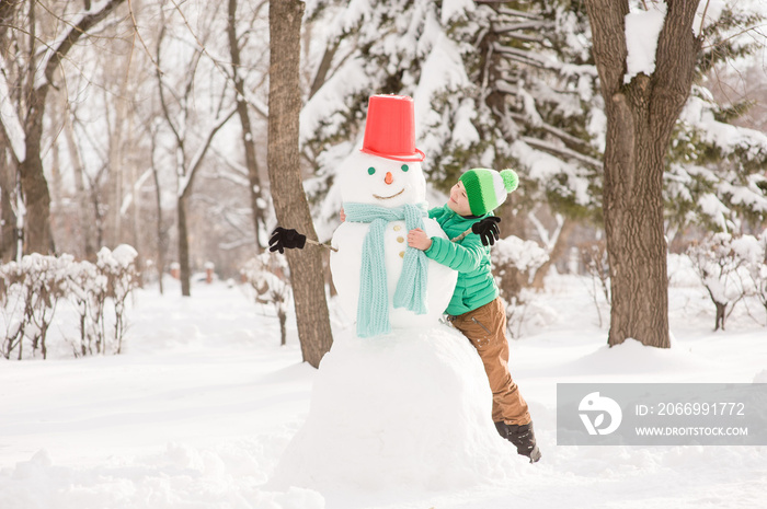 Happy little boy building snowman. Empty space for text