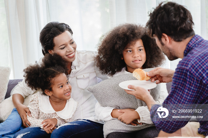 Lovely home happy family living together in living room father mother playing with daughter mix race.