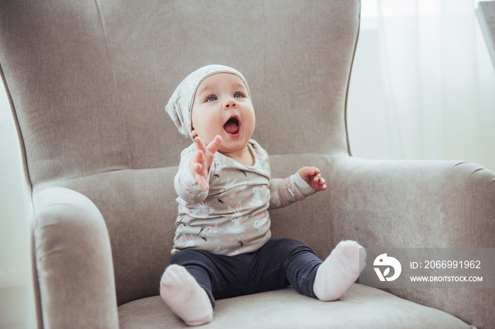 1 year girl wearing stylish clothes, sitting in a vintage chair in the room.