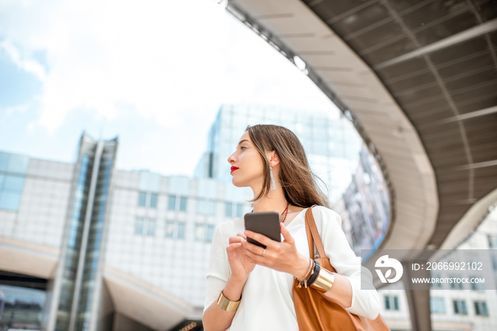 Young businesswoman standing with phone near the Parliament building of European Union in Brussel city