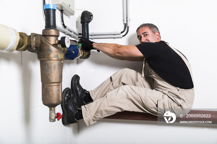 Plumber near water pipes opening water tap