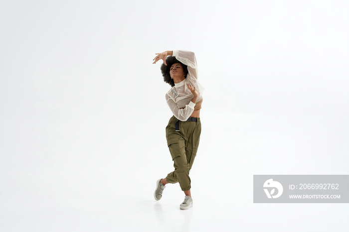 Young black woman dancing on white background