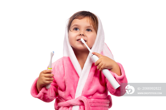 Emotional сlose up cute little girl in pink bathrobe cleaning teeth with electrical toothbrush Isolated on white background