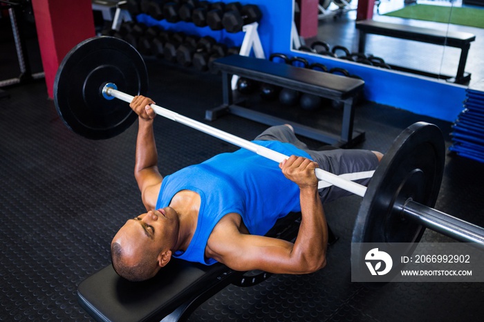 Male athlete doing bench press in fitness studio