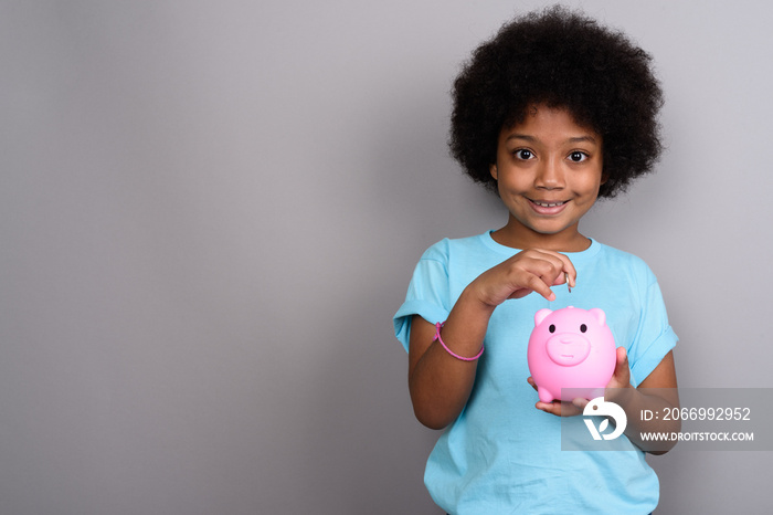 Young cute African girl against gray background