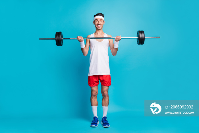 Full body photo of astonished positive guy arms lift barbell unbelievable result isolated on blue color background