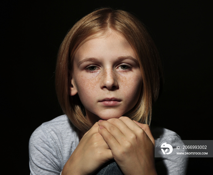 Portrait of sad little girl on black background