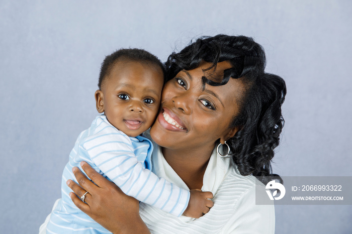 Beautiful African Amercian Woman wHolding Her Baby boy on a Gray Background