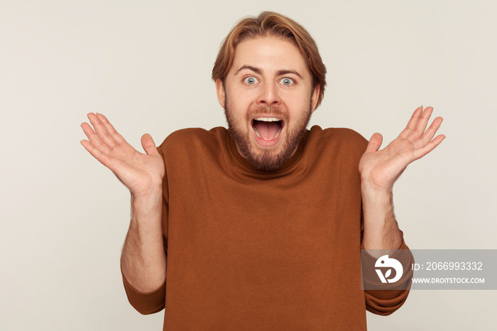 Oh my god, wow! Portrait of happy astonished excited bearded man standing with open mouth and screaming in sudden shock, surprised by unbelievable success. studio shot isolated on gray background