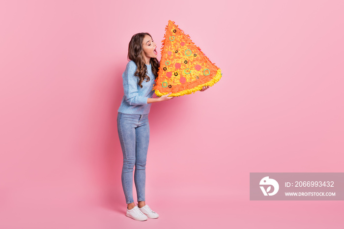 Full length body size view of attractive funny girl holding biting fake big pizza isolated over pink pastel color background