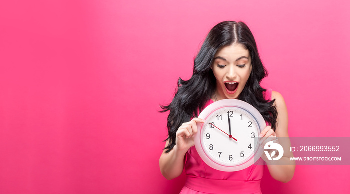 Young woman holding a clock showing nearly 12