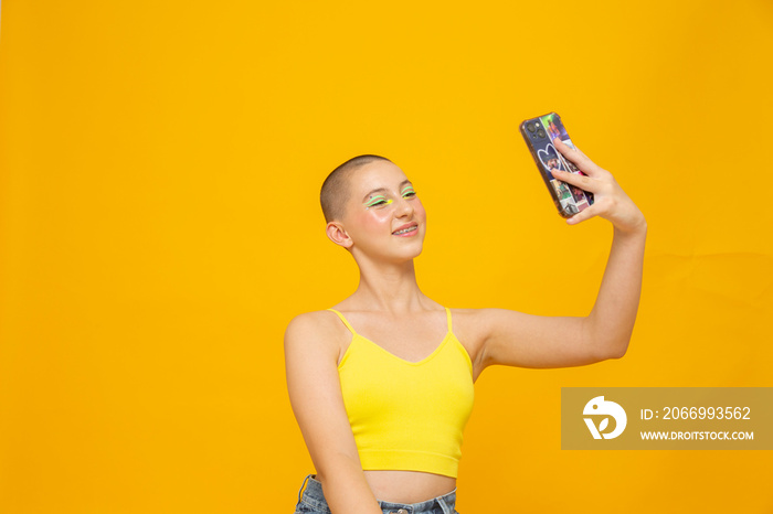 Studio shot of girl with neon colored make-up taking selfie