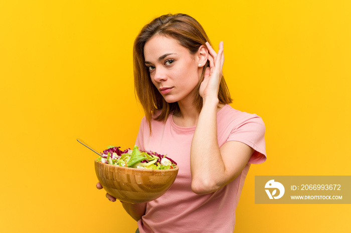 Young healthy woman holding a salad trying to listening a gossip.