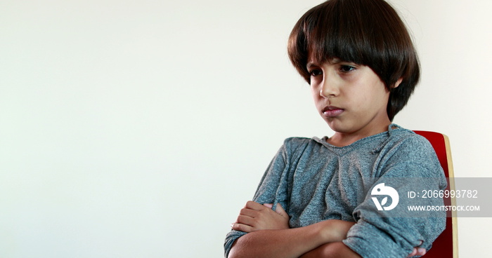 Upset young boy of mixed race crossing arms. Angry child with arms crossed