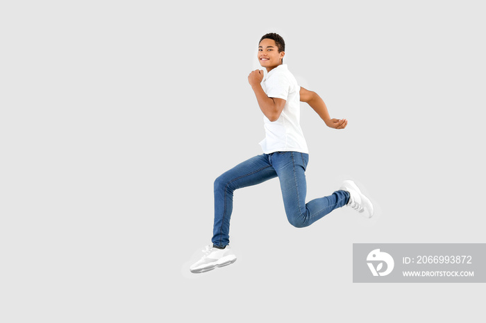 Jumping African-American teenager boy on white background