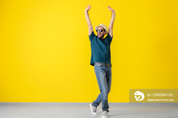 Handsome young man dancing near color wall