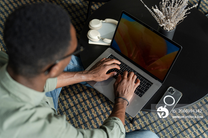 Young man with laptop sitting in office lounge