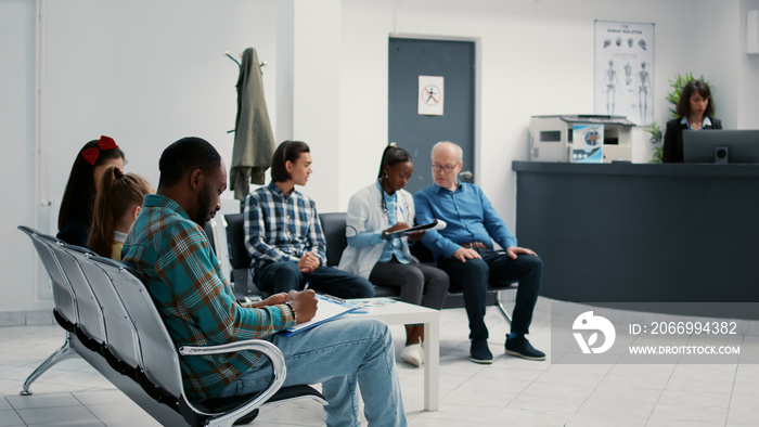 Diverse group of patients sitting in waiting room at hospital, reception desk for checkup appointment and consultation. Waiting area lobby with people at medical examination facility.