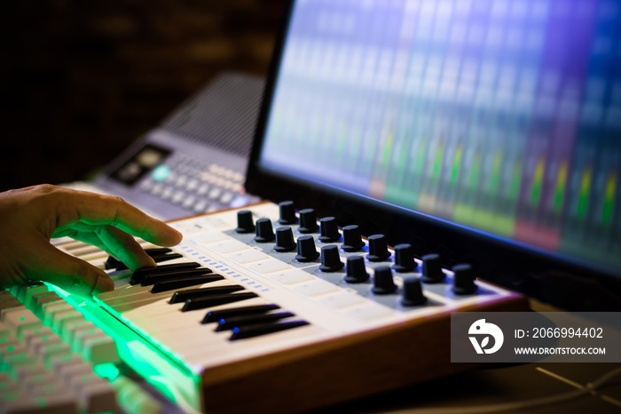 composer hands playing midi keyboard for recording song on computer in home studio