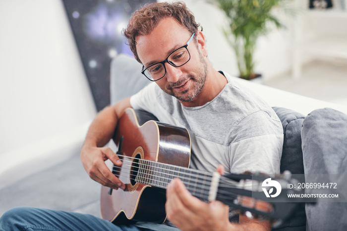 Man playing acoustic guitar in the living room.