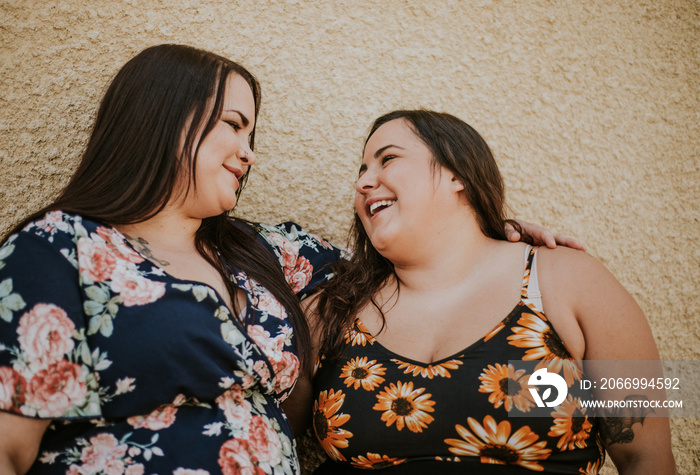 closeup of 2 plus size Metis women smile and look at each other