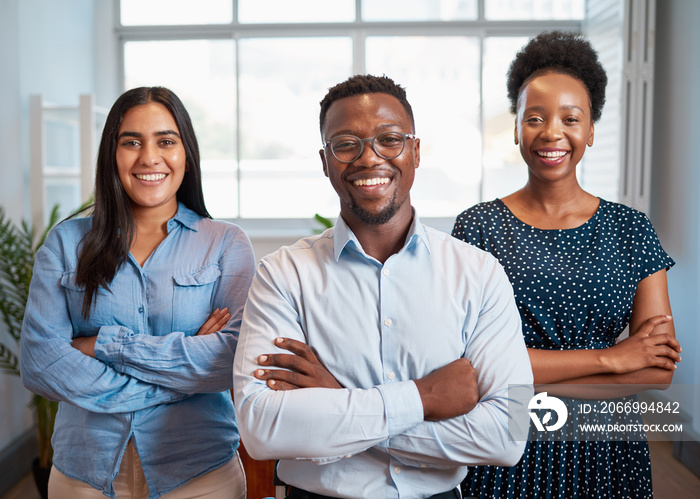 Group of smiling business people pose arms folded in office, diverse trio