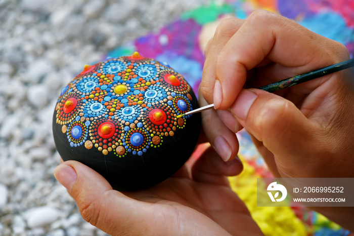 Drawing with a brush a mandala on a stone