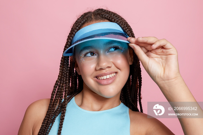 Studio portrait of smiling girl wearing sun visor