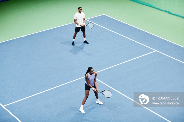 Minimal high angle shot of African American couple playing tennis in pair at indoor court, copy space