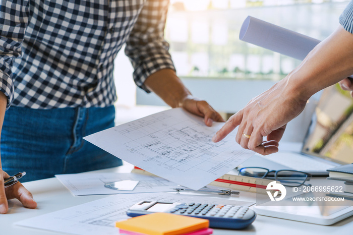 engineer Hand Drawing Plan On Blue Print with architect equipment discussing the floor plans over blueprint architectural plans at table in a modern office.