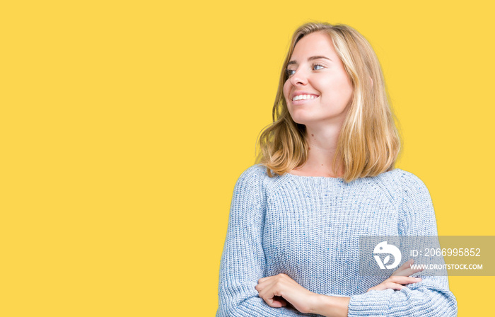 Beautiful young woman wearing blue sweater over isolated background smiling looking to the side with arms crossed convinced and confident