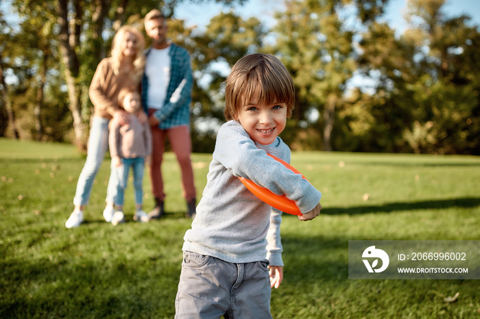 Love is a family value. Little boy playing frisbee in the park on a sunny day