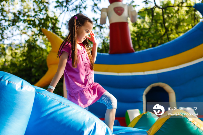 Happy little girl having lots of fun on a jumping castle during sliding.