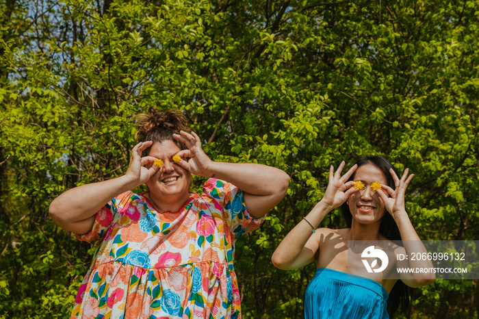 portrait of 2 friends with dandelions in front of eyes