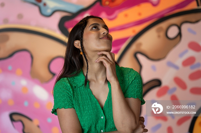 Smiling young woman standing in front of mural