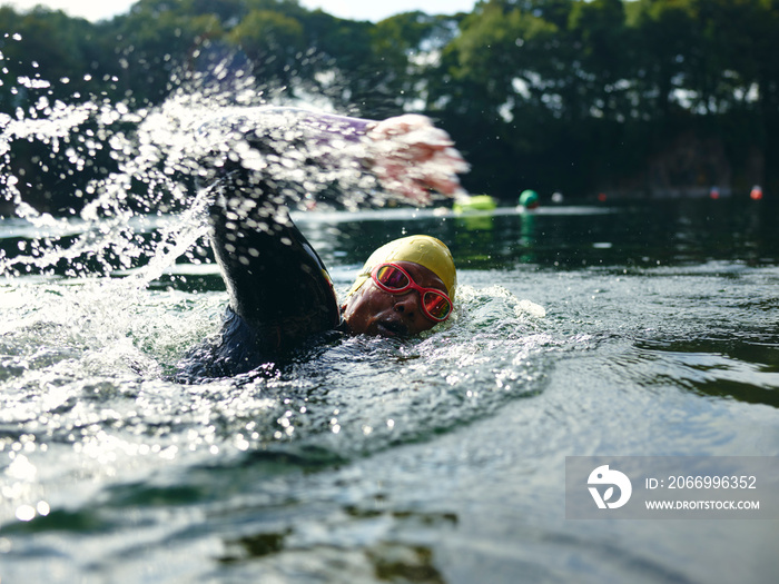 Woman in swimming cap and goggles swimming in river