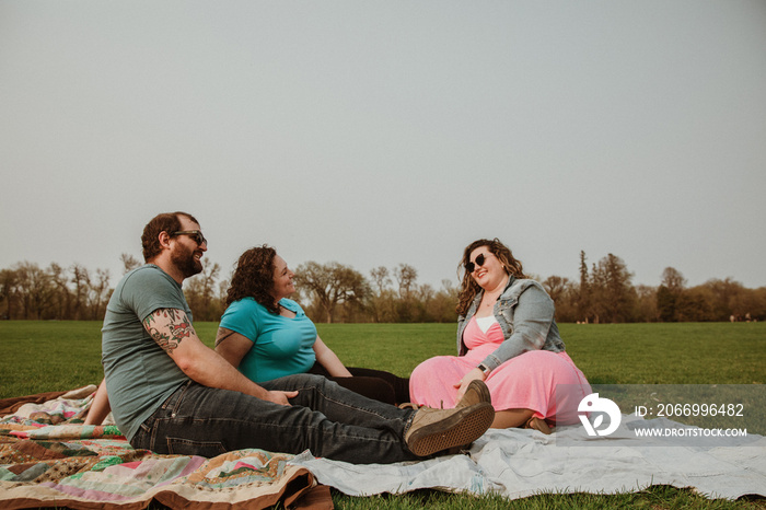 3 friends hang outside in the park on a blanket