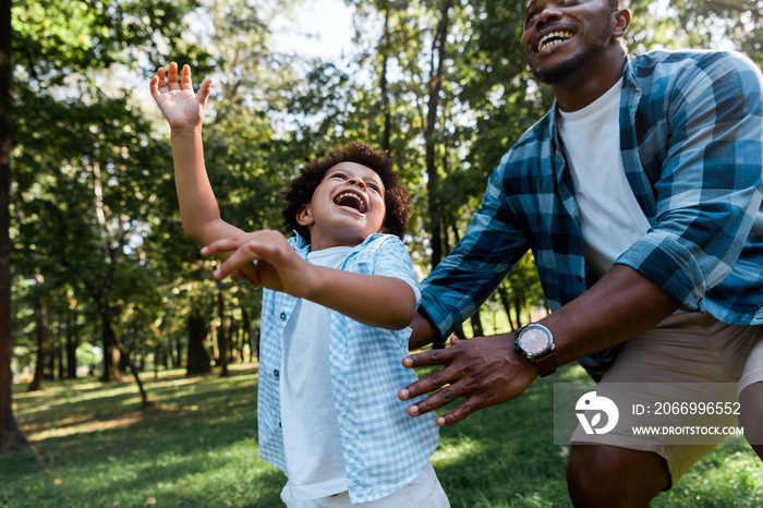 cropped view of positive african american father near happy kid in park