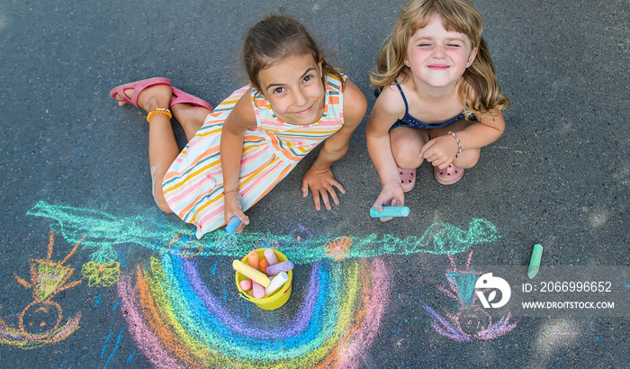 Children paint a rainbow on the asphalt. Selective focus.