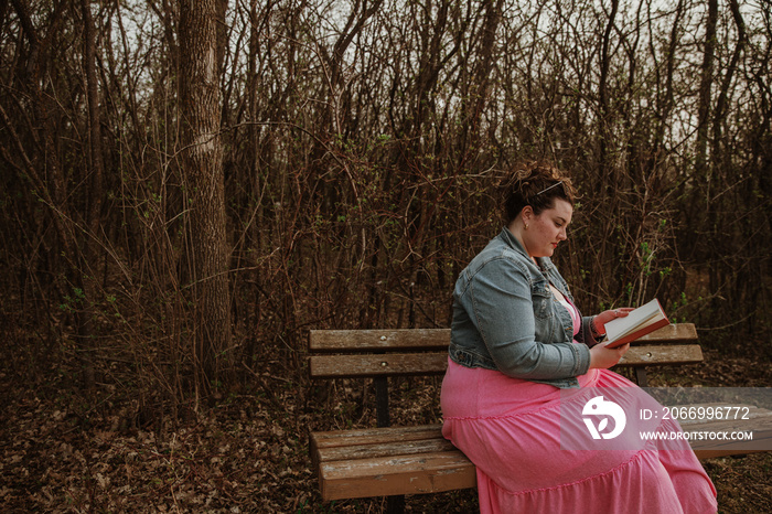 woman sits on bench reading a book