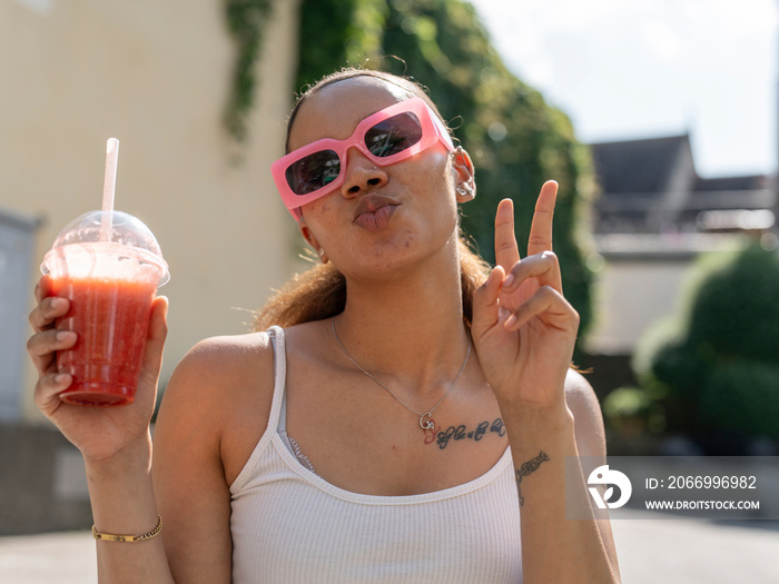 Portrait of young woman in sunglasses with smoothie