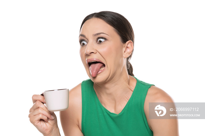 Disgusted young woman with a cup of hot drink on a white background